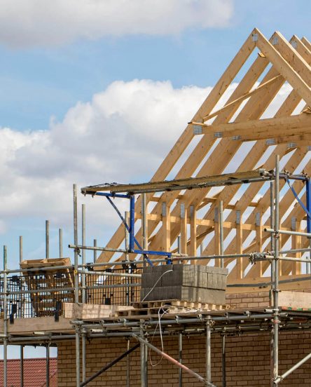 Construction industry. Timber framework of house roof trusses with scaffold on a building being built on a new housing estate.